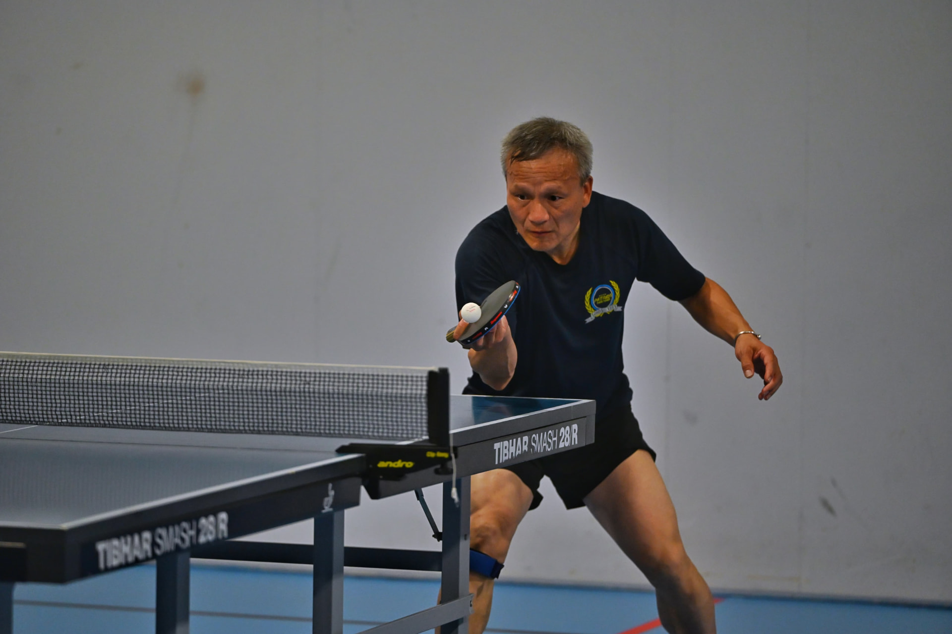 A veteran player leaning in for a controlled forehand close to the table