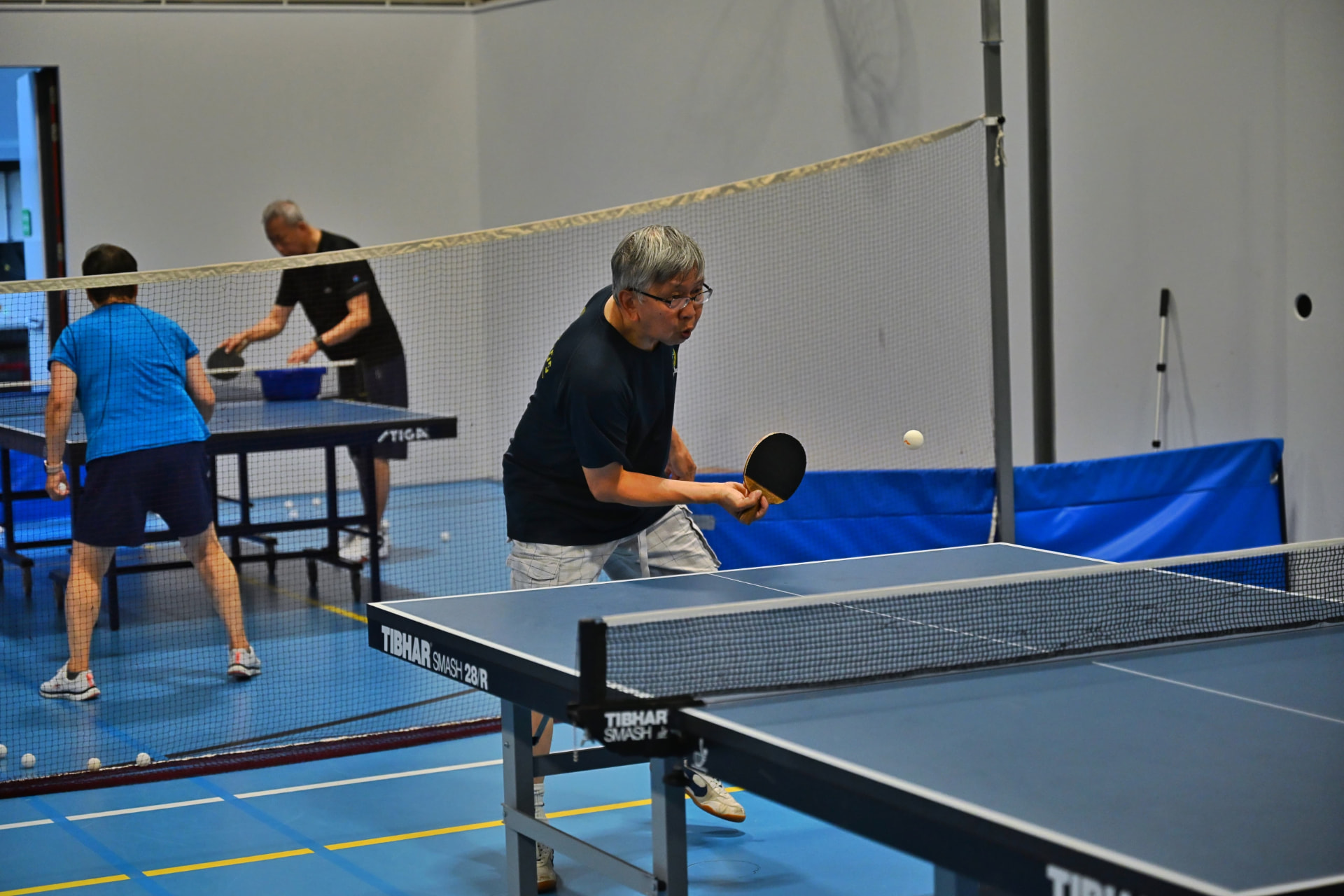 Training session with a basket of balls while other members practise in the background